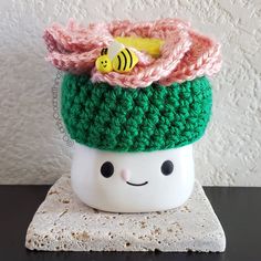 a crocheted cup with a smiling face and a bee sitting on top of it