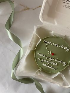 a green cake in a white box with ribbon on the side that says congratulations to an unknown person