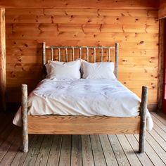 a bed with two pillows on top of it in a room that has wooden walls