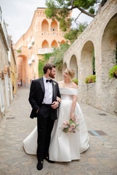 a bride and groom are walking down the street