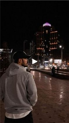 a man standing in front of a city street at night with his back turned to the camera