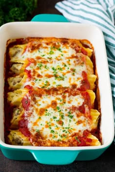 a casserole dish with meat, cheese and sauce in a blue baking dish