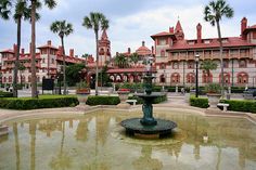 a fountain in front of a building with palm trees