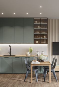 a kitchen with wooden flooring and green cabinetry next to a dining room table