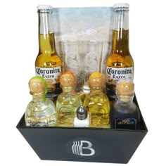 three bottles of corona extra are sitting in a black box next to two empty glasses