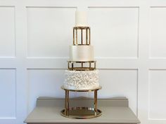 three tiered wedding cake with white frosting and gold accents on a silver stand