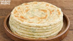 a wooden bowl filled with flatbreads on top of a table