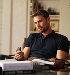 a man sitting in a chair holding a pipe and looking at something on the table