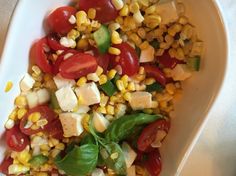 a white bowl filled with corn and tomatoes