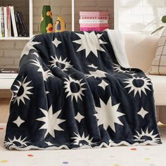 a black and white blanket sitting on top of a couch next to a book shelf