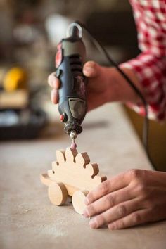 a person uses a drill to cut wood with a small toy car on the table