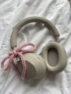 a pair of headphones laying on top of a white bed with a pink cord