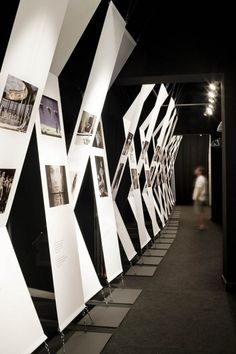 an art exhibit with black and white pictures on the wall, along with people walking by