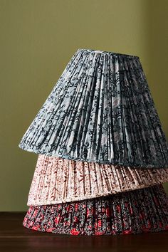 two lampshades stacked on top of each other in front of a green wall