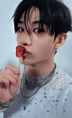 a young man with black hair eating a piece of food