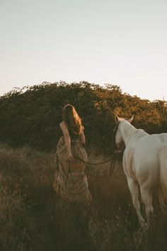 a woman is walking her horse through the field