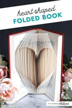 an open folded book with the title heart shaped folded book on it and flowers in front