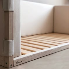 the bottom half of a bed frame with wooden slats and white sheets on it