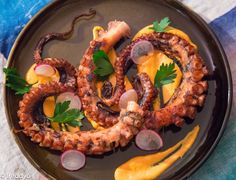 an octopus dish is served on a black plate