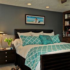 a bedroom with blue and white bedding, green accents and a chair in front of the bed