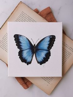 a blue butterfly sitting on top of an open book