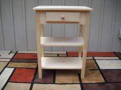 a small wooden table sitting on top of a carpeted floor next to a wall