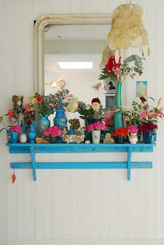 a blue shelf with flowers and vases on it