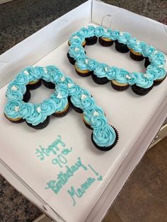 two cupcakes are shaped like the number 50 and have blue frosting on them