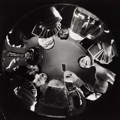 a group of people sitting around a table with drinks and playing cards on the table