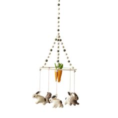 three stuffed animals hanging from a mobile with carrots on it's sides and two bunnies attached to the strings