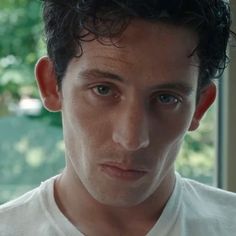 a close up of a person wearing a white t - shirt and looking at the camera