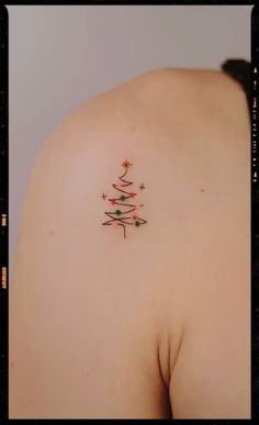 a woman's back with a small christmas tree tattoo on it