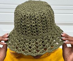 a woman wearing a green crochet hat covering her face