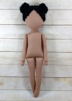 a doll with black hair is posed on a white wooden background and looks down at the floor