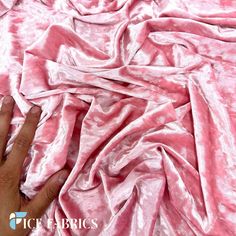 a person's hand on top of a pink crushed velvet material with the word pick fabric