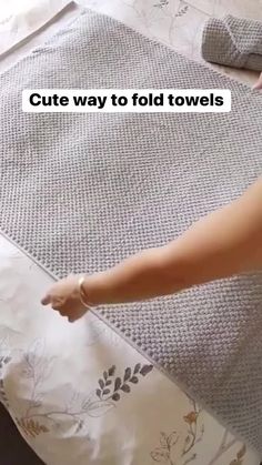 a person is pointing at a towel on top of a bed with the words cute way to fold towels