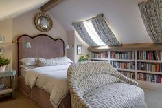 a bed sitting in a bedroom next to a book shelf filled with lots of books