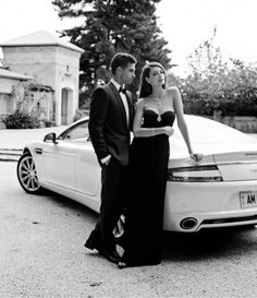 a man and woman standing next to a white car