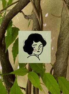 a drawing of a woman's face on a piece of paper hanging from a tree