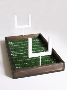 a wooden tray with grass in it and two white square holders on the top one