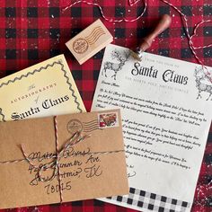 two envelopes and a rubber stamp sitting on top of a plaid cloth covered tablecloth