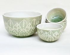 four bowls with designs on them sitting next to each other in front of a white background