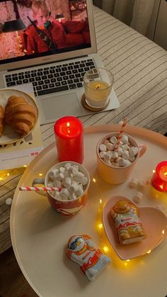 a laptop computer sitting on top of a table filled with desserts and marshmallows