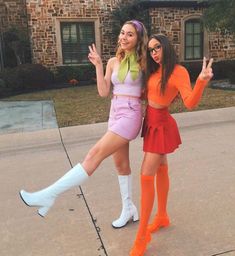 two women dressed in costumes posing for the camera with one holding her hand up and the other pointing