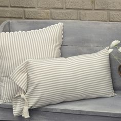 two pillows sitting on top of a bench next to a vase with flowers in it