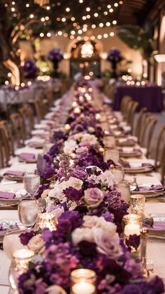 a long table is set with purple and white flowers, candles, and napkins