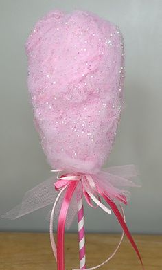 a pink candy lollipop with a bow on it's head is sitting on a table