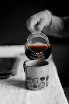 someone pouring coffee into a cup on top of a table