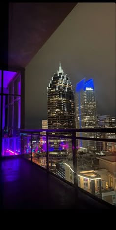 the city skyline is lit up at night with purple lights and buildings in the background