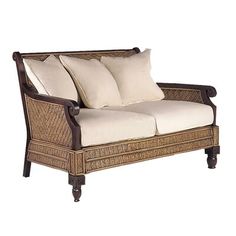 a wicker couch with white pillows on it's arm and backrests